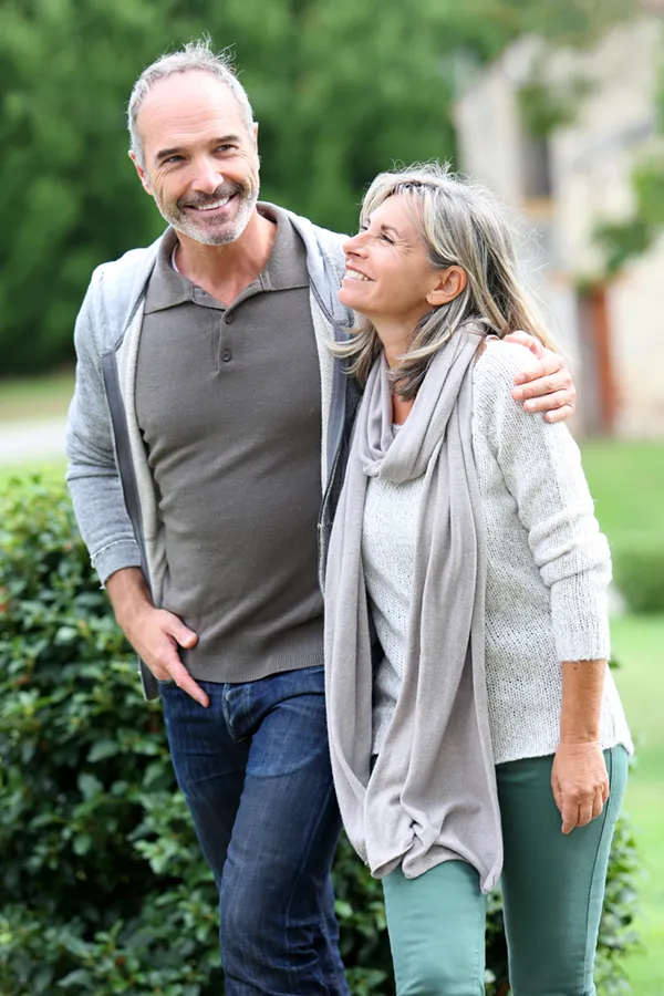 Bioidentical-Hormone-Therapy-Treatment A mature couple in gray toned clothes and jeans walk happily outside, happy with their successful bioidentical hormone treatments from David Garcia, D.O. in Nashville Metro.