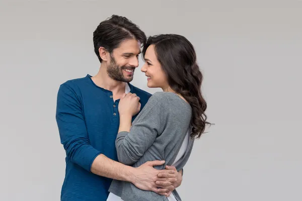 Erectile-Dysfunction-Doctor A man in a blue shirt embracing a woman in a gray shirt smiles due to his successful erectile dysfunction care from David Garcia, D.O. in Nashville Metro.