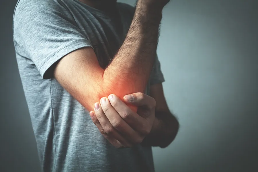 Exosomes-for-Elbow-Pain-Clinic A man holds his inflamed elbow. Schedule exosome therapy for elbow pain from David Garcia, D.O. in Nashville Metro.
