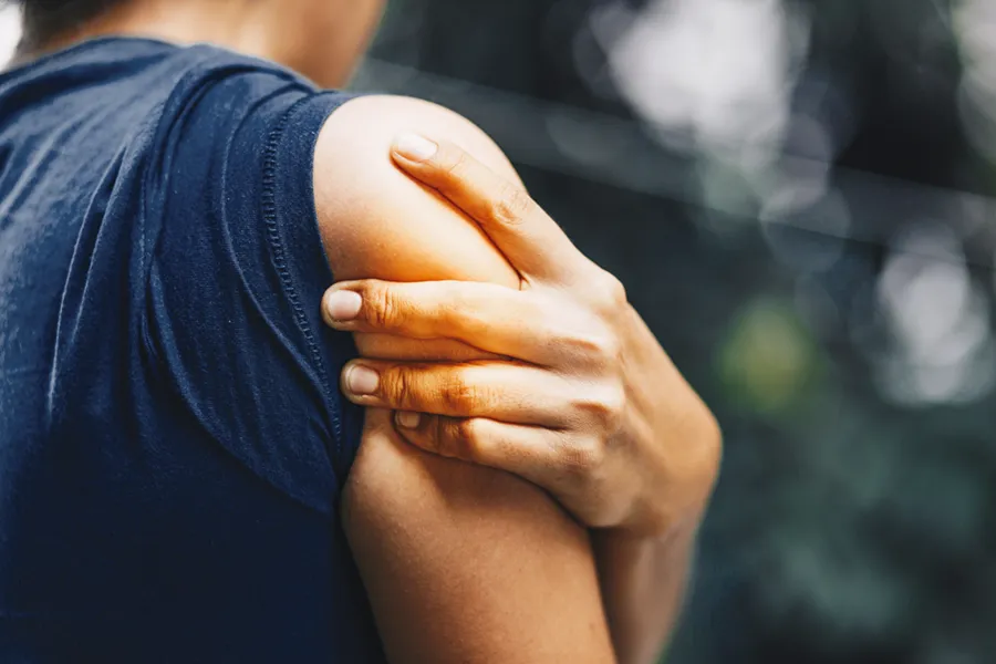 Exosomes-for-Shoulder-Pain-Clinic A woman holds her inflamed shoulder. Get exosome therapy for shoulder pain from David Garcia, D.O. in Nashville Metro.