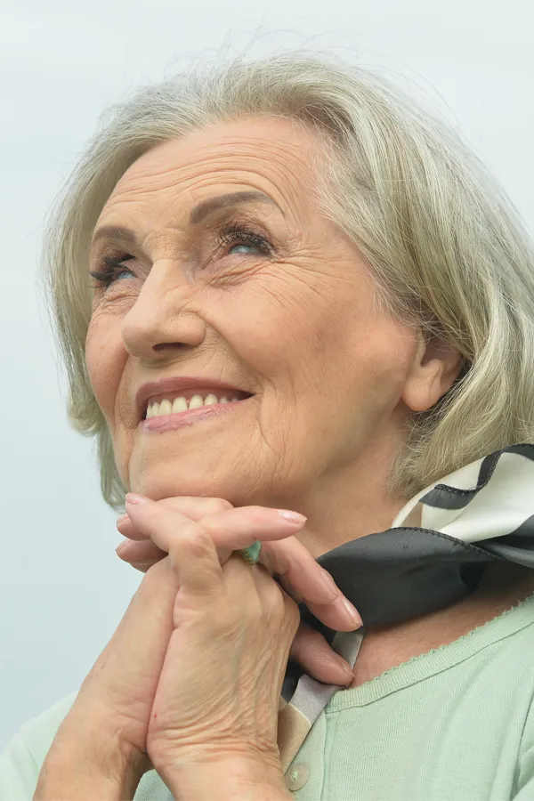 Hot-Flashes-and-Night-Sweats-Treatments An older woman holds her hands together under her chin and looks up at a cool sky smiling. Get treatment for hot flashes and night sweats from David Garcia, D.O. in Nashville Metro.