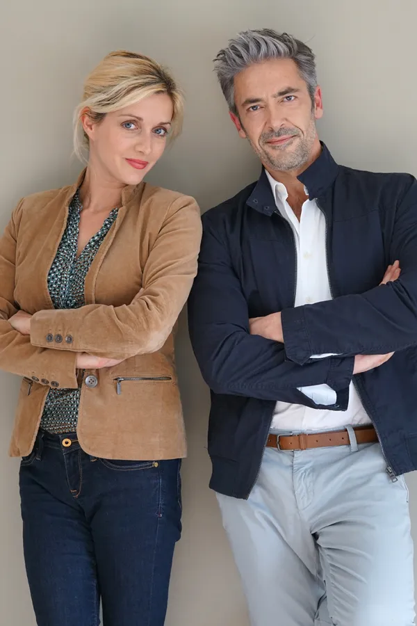 Hyperthyroidism-Treatment A middle-aged couple stand against a wall smiling with folded arms. Get hyperthyroidism treatment from David Garcia, D.O. in Nashville Metro.