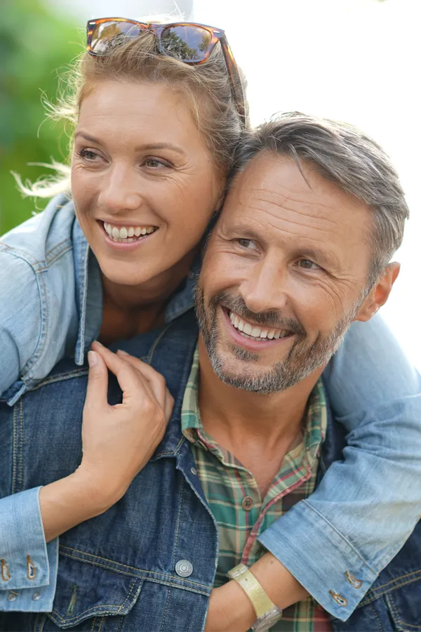Hypogonadism-Treatment A couple in denim jackets embrace playfully outdoors. Get hypogonadism treatment from David Garcia, D.O. in Nashville Metro.