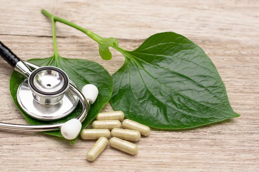Integrative-Medicine-Clinic A stethoscope, leaves, and medicine capsules on a wood table, representing Integrative Medicine provided by David Garcia, D.O. in Nashville Metro.