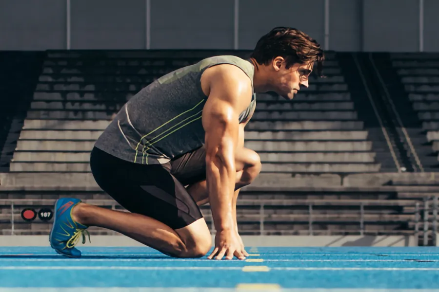 Lean-Muscle-and-Recovery-Clinic A white man kneels at the starting line on a track, determined to do his best. Get treatment for lean muscle loss and recovery from David Garcia, D.O. in Nashville Metro.