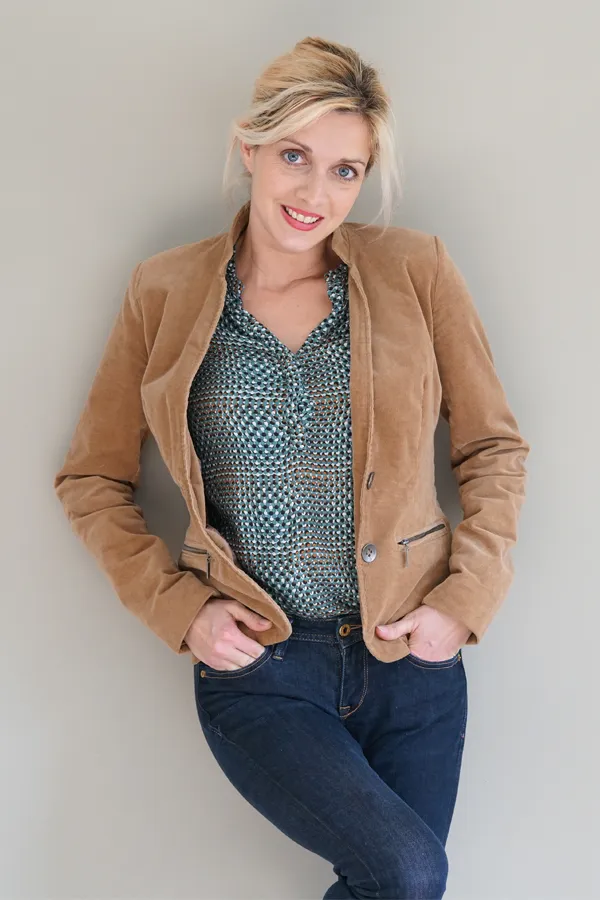 Metabolic-Syndrome-Treatment A smiling blonde woman in a tan leather jacket leans against a gray wall. Schedule metabolic syndrome from David Garcia, D.O. in Nashville Metro.