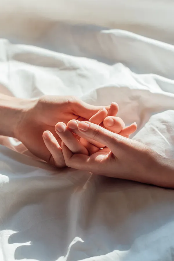 PT141-for-Women-Treatment A close up of a man and woman's hands lightly clasping on a bedsheet, representing successful PT141 sexual wellness treatment for women from David Garcia, D.O. in Nashville Metro.