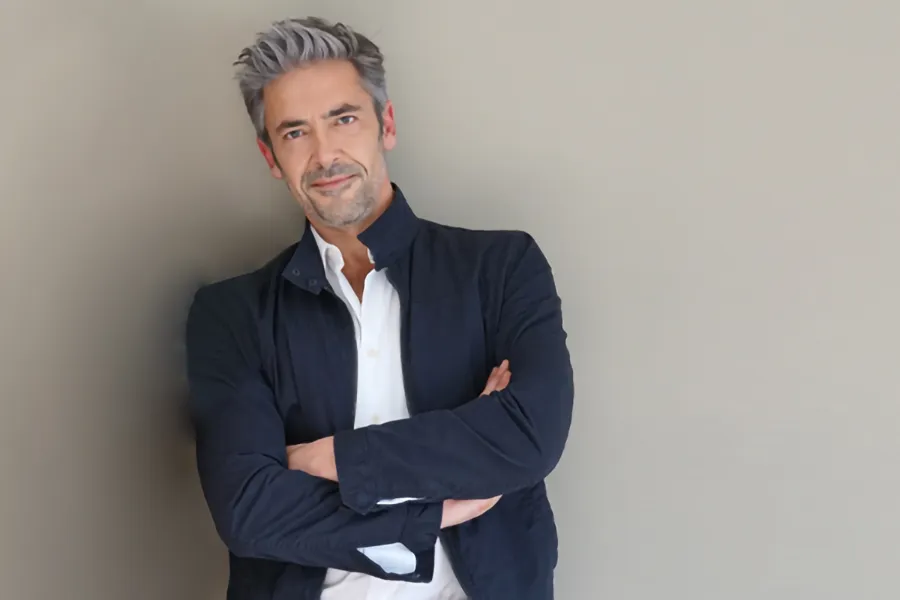 Testosterone-Low-T-Solutionsn-Clinic A middle-aged man in a white shirt and dark blue jacket leans against a gray wall smiling. Get testosterone for Low T from David Garcia, D.O. in Nashville Metro.