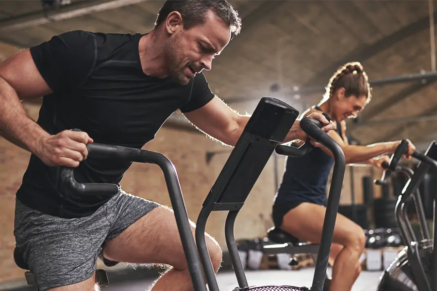 Tirzepatide-Doctor A couple in a brick gym work as hard as they can on exercise bikes, inspired by successful Tirzepatide treatment from David Garcia, D.O. in Nashville Metro.